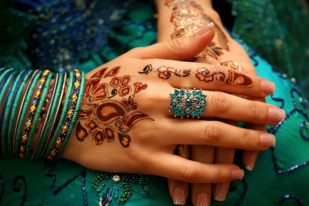Mehndi detail on a bride's hands with green bangles